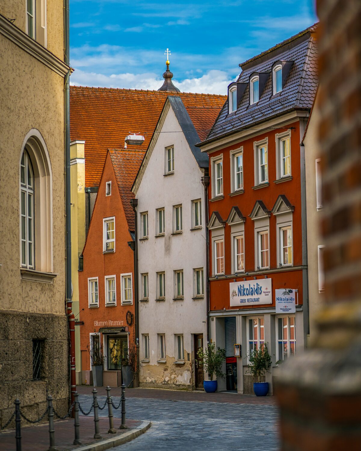Enge Gasse in der Landshuter Altstadt mit gotischen Bürgerhäusern in Ocker, Weiß und Rot