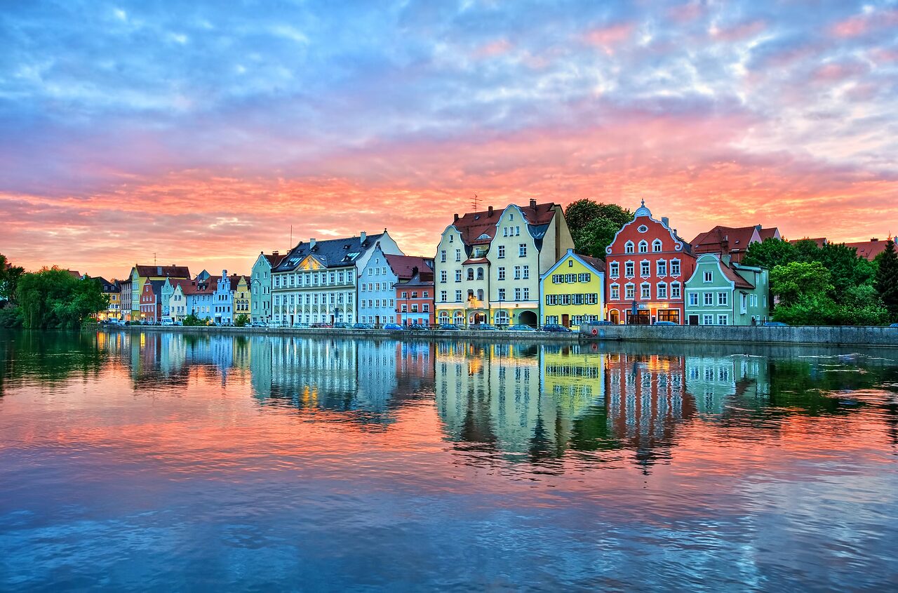 Häuserzeile am Ufer der Isar in Landshut, im Wasser gespiegelt, bei rot gefärbtem Abendhimmel