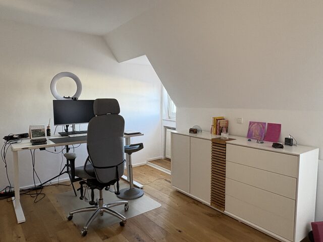 Arbeitsplatz mit höhenverstellbarem Schreibtisch, Monitor, Bürostuhl und Sideboard in einem eigenen Raum