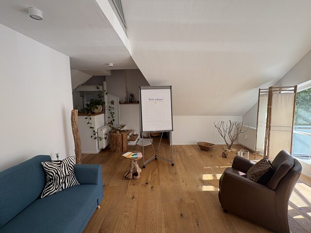 Aufgestelltes Flipchart im Hauptraum, daneben Sofa, Ledersessel und Moderationskarten auf einem Holztisch