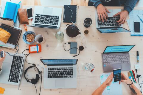 Symbolbild Co-Working: Arbeitsplätze mit Laptops von oben